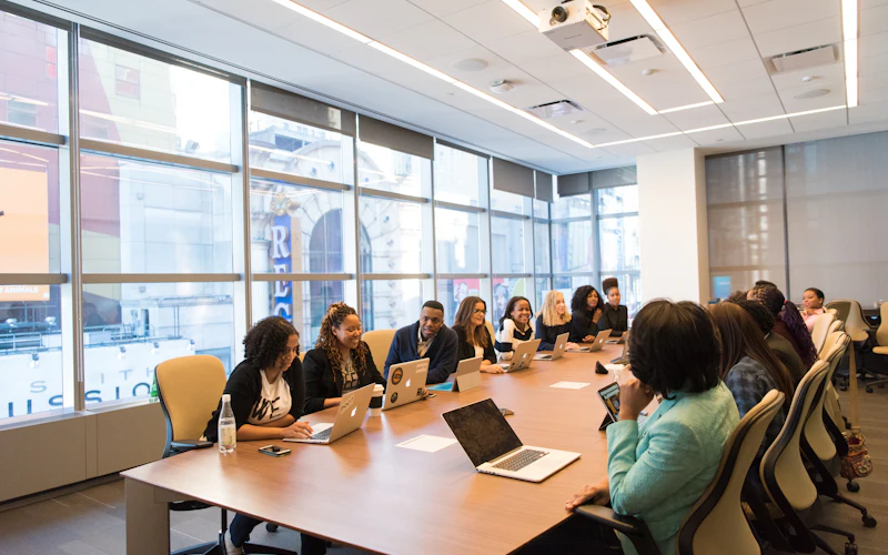 A team meeting around a boardroom table with laptops