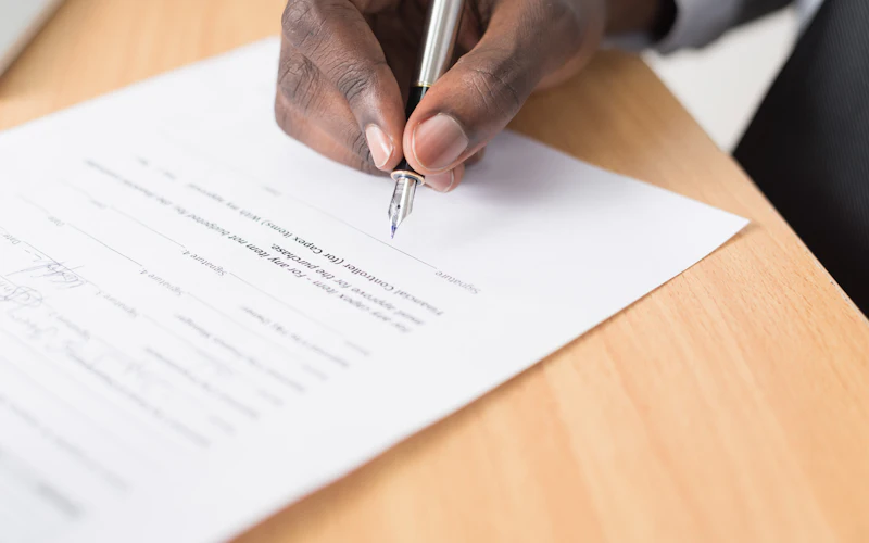 A person signing a document at a desk